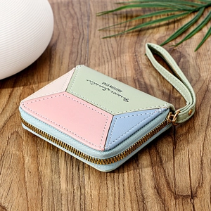 Detail of color-block PU leather wallet with hand strap and gold metal zipper on wood