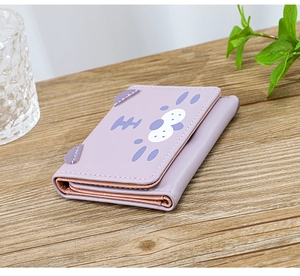 Détails des coutures et de la texture du portefeuille chat violet sur table en bois