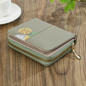 Detailed close-up of a green floral wallet with a gold zipper on a wooden table
