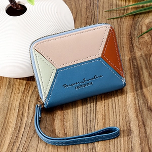 Short patchwork leather wallet for women with wrist strap and zip closure on wooden table
