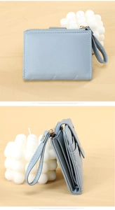 Close-up of light blue leather wallet featuring wavy stitching and golden zipper hardware