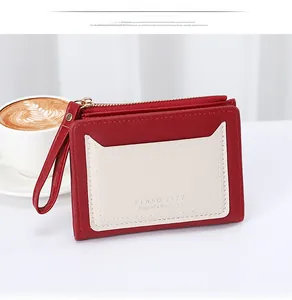 Close-up of red and white leather card wallet with zipper and wrist strap detail