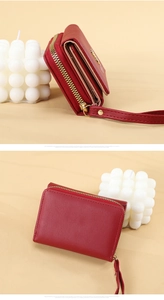 Detail view of dark red PU leather trifold wallet with gold zipper and wrist strap