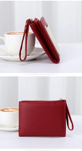 Detail view of red leather wallet featuring card slots, wrist strap and gold zipper