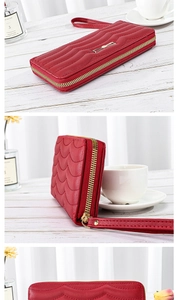 Detail view of red quilted leather wallet with gold bow accent and wrist strap