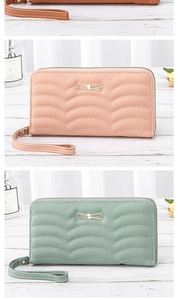 Detail of long quilted wallet with metal bow and wristlet in pink and green colors