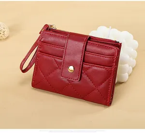 Detail of burgundy quilted faux leather card holder with zipper pocket and wrist strap