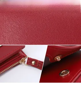 Detail of red pebbled leather wallet featuring light gold metal zipper and snap button
