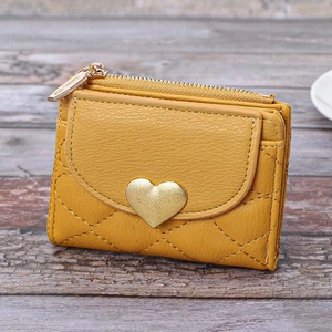 Mustard yellow mini wallet with heart clasp and quilted faux leather on wood background