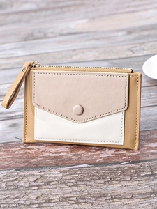 Close-up of tricolor leather card holder with gold zipper on a rustic wooden desk