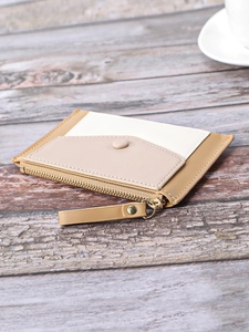 Close-up of tricolor slim wallet showing fine stitching and gold zipper on wooden surface