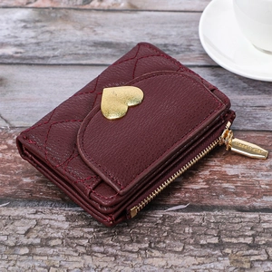 Macro view of burgundy quilted faux leather wallet featuring a golden heart metal clasp