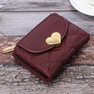 Detailed macro view of embroidered heart stitching and gold clasp on burgundy wallet