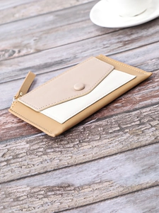 Detail view of slim color-block wallet with snap pocket on a vintage wood background