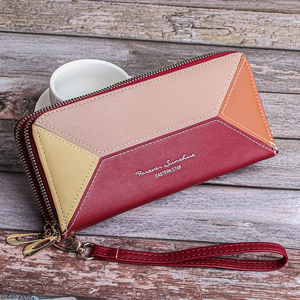 Detail of color-block wallet with dual zipper and detachable wrist strap on wood