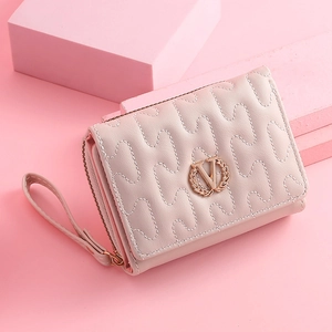 Detailed close-up of quilted pink wallet with golden circular V logo and leather strap