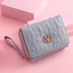 Macro view of blue quilted faux leather wallet with metallic V logo and wrist strap