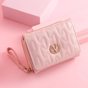 Detail of pink wave-quilted short wallet featuring metal V-logo and wristlet strap