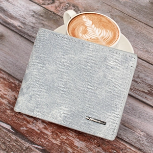 Short men's grey fabric bifold wallet on a wooden table next to a latte coffee cup