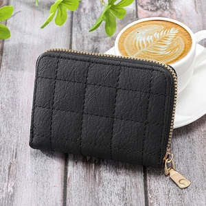 Chic black quilted card holder with gold zipper on a minimalist coffee table setting