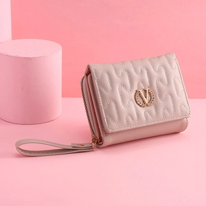 Detail of lavender pink quilted PU leather clutch with gold V logo and wrist strap