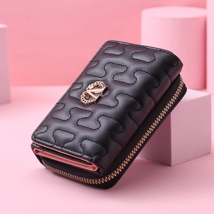 Detail view of black textured leather wallet with gold metal logo and pink lining