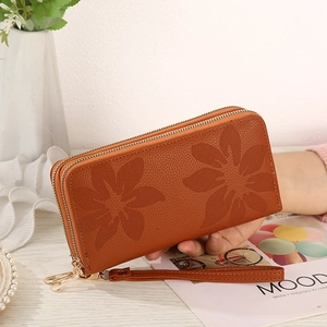Detail of brown leather double-zipper wallet with flower embossing and wrist strap