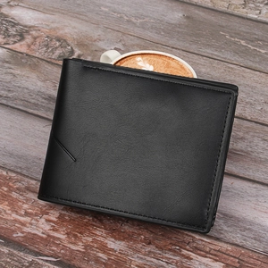 Detail view of black litchi pattern leather wallet on wooden surface with coffee