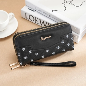 Détail du portefeuille noir à double zip avec motif floral matelassé et dragonne amovible