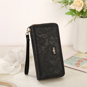 Detailed view of black floral embossed leather wallet with clover-shaped silver metal clasp