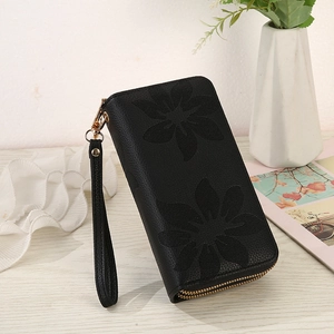 Close-up of black long wallet with hollow floral pattern and wrist strap on wood desk