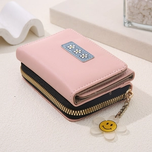 Close-up of pink three-fold wallet with floral patch, side zipper and daisy pendant