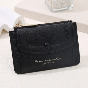 Close-up of black litchi grain leather wallet with snap flap and gold sunshine text