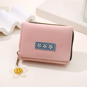 Close-up of pink short wallet featuring a daisy patch and yellow smiley flower charm