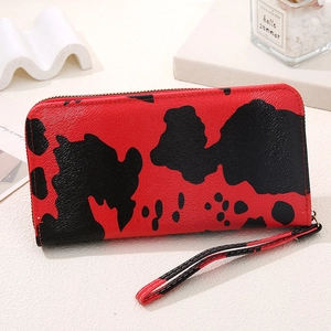 Detail of red cow print long wallet with zipper and wrist strap on aesthetic background