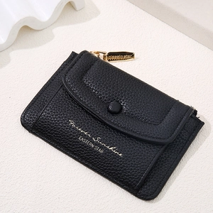 Detail view of black lychee grain faux leather mini wallet with gold zipper and lettering