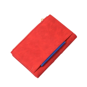 Detail of red pebbled faux leather travel passport wallet with golden zipper and blue slot