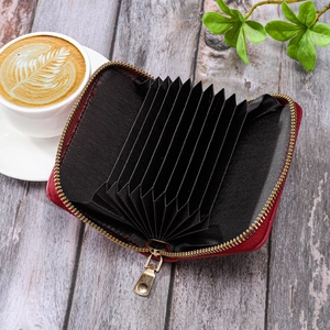 Detail view of red leather accordion card holder with multiple slots on a wooden desk