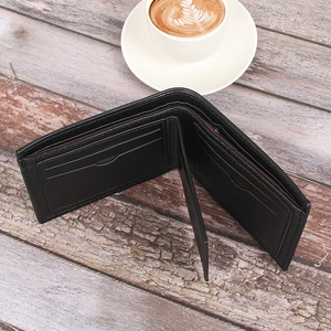 Detail view of a black leather bifold wallet with multiple card slots on a wooden table