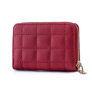 Detail of red quilted faux leather card holder wallet with golden metal zipper closure