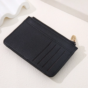 Detail of slim black pebbled leather card holder with three slots and gold zipper pocket