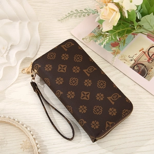 Vintage brown long leather wallet with monogram pattern and gold zipper on wooden desk