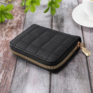 Detail of black quilted leather card holder with premium gold zipper on a wooden desk