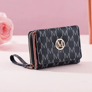 Detail of a black trifold wallet with grey M-pattern and gold logo on pink surface