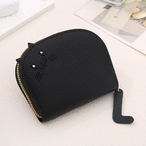 Short black leather card wallet with cute cat ears and gold zipper detail shown on a desk