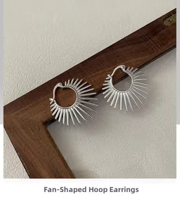 Détail macro de boucles d'oreilles argentées en éventail sur cadre en bois foncé