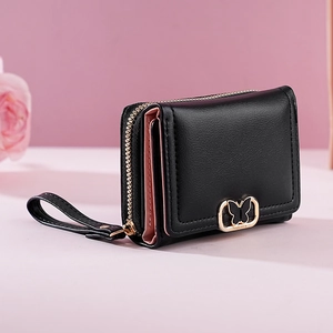 Gros plan du portefeuille noir à trois volets avec boucle papillon dorée et rose