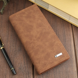Detail of vintage brown long leather wallet with stitching and metal badge on wood desk