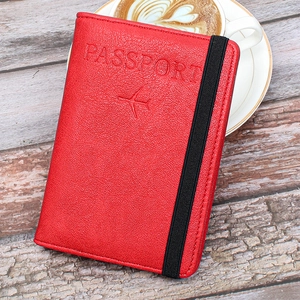Macro detail of red leather passport cover with airplane embossing and elastic band