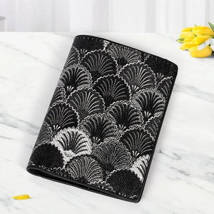 Detail of black fabric wallet featuring silver wave embroidery and leather edges